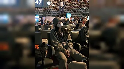 Suzy fans, exhausted during airport layover—tilting head and sitting wide
